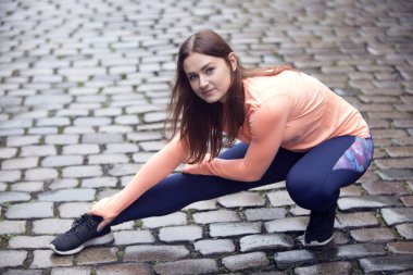 genç esmer kadın kaldırımda germe