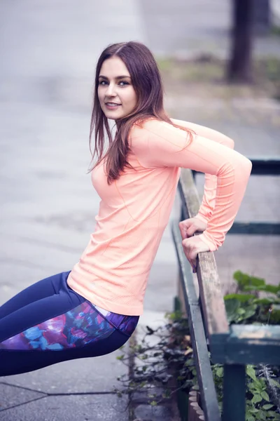 Young woman strechting outdoors on pavement — Stock Photo, Image