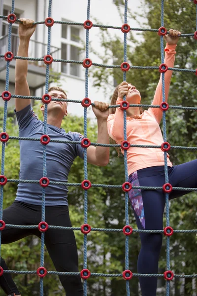 Pareja deportiva subiendo por una red — Foto de Stock