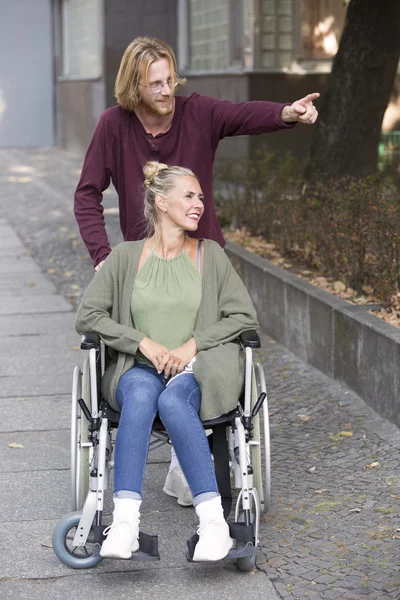 Mujer en silla de ruedas y hombre joven mostrándole algo —  Fotos de Stock