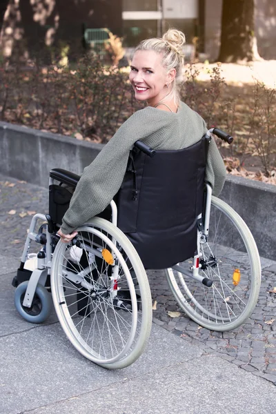 Mulher em cadeira de rodas sorrindo para a câmera — Fotografia de Stock