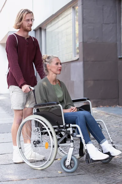 Mujer en silla de ruedas y hombre ayudándola — Foto de Stock