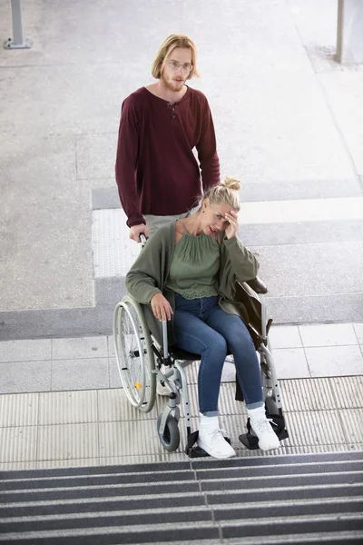 Mulher em uma cadeira de rodas na frente de escadas — Fotografia de Stock