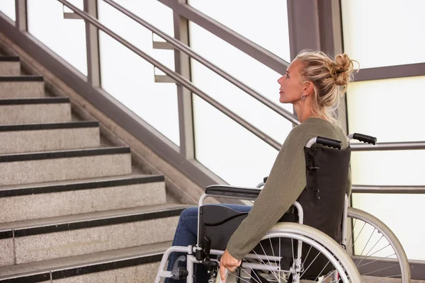 Mujer en silla de ruedas delante de las escaleras — Foto de Stock