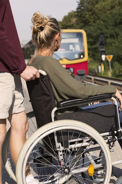 Mulher em cadeira de rodas em uma estação de trem — Fotografia de Stock