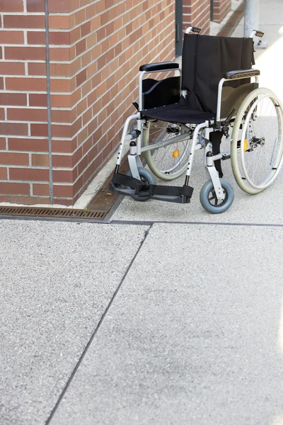 보도에 벽에 의해 버려진된 휠체어 — 스톡 사진