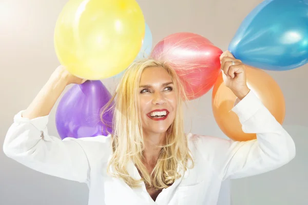 Portrait of blond woman with colorful balloons — ストック写真