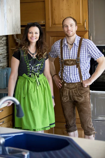 Coppia bavarese in piedi in cucina e sorridente — Foto Stock