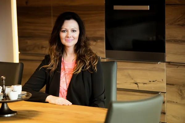 Mujer sentada en la mesa y sonriendo —  Fotos de Stock