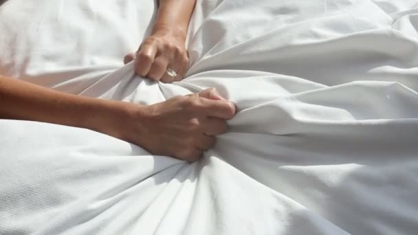 Χέρια του αρπάζοντας μια λευκή γυναίκα κουβέρτα στο κρεβάτι και χαλαρώνει — Αρχείο Βίντεο