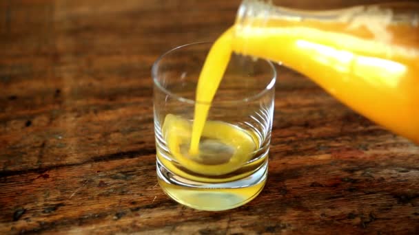 Gros plan de jus d'orange versé dans un verre et une bouteille à côté — Video