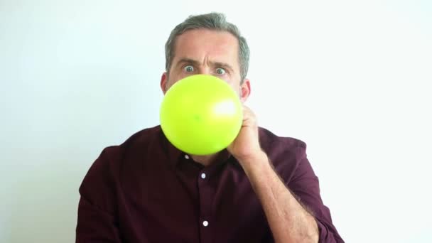 Bonito homem soprando fora um amarelo balão até que explode — Vídeo de Stock