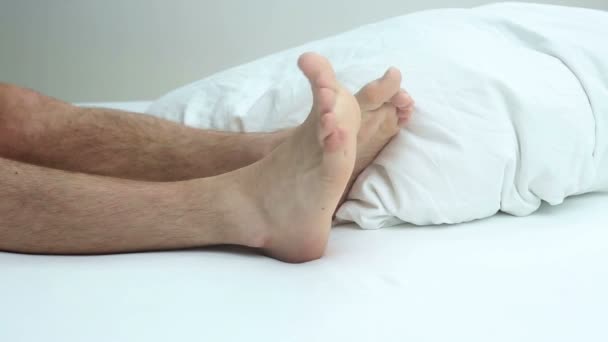 Primer plano de las piernas peludas y los pies desnudos en la cama — Vídeo de stock