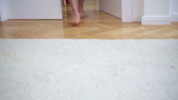 Vértes mezítláb az ember besétál egy szobába, fehér szőnyeg — Stock videók