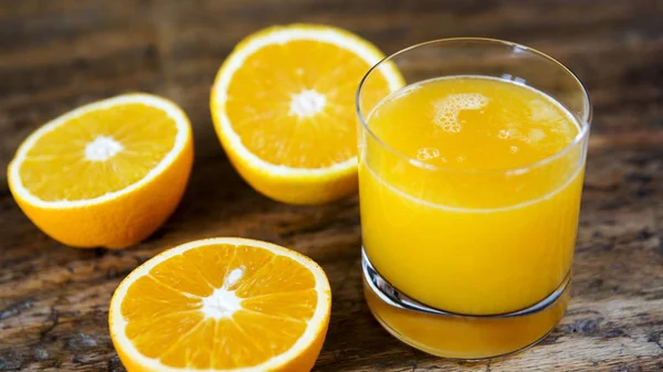 Vidro de suco de laranja fresco e laranjas cortadas — Fotografia de Stock