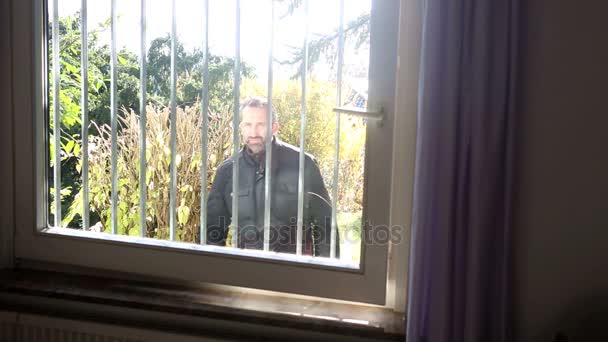 Грабитель пытается влезть в окно с железными решетками — стоковое видео