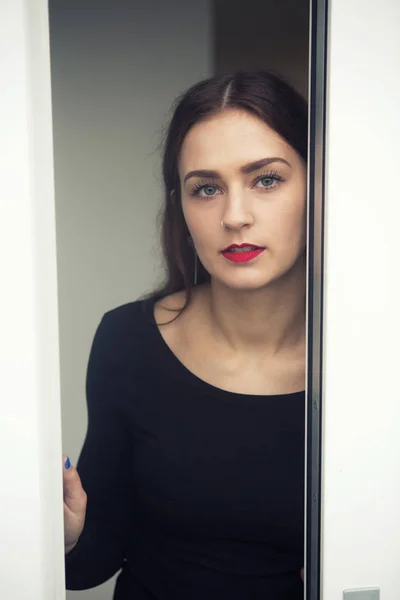 Portrait of young woman standing by open window — Stock Photo, Image