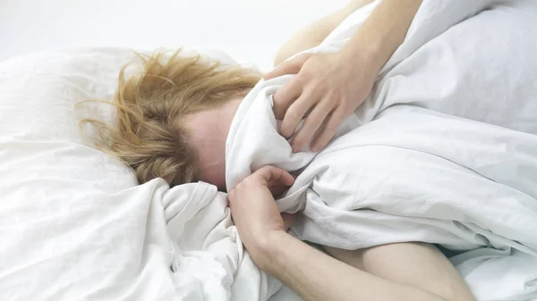 Red-haired young man lying in bed covering up his face — Stock Photo, Image