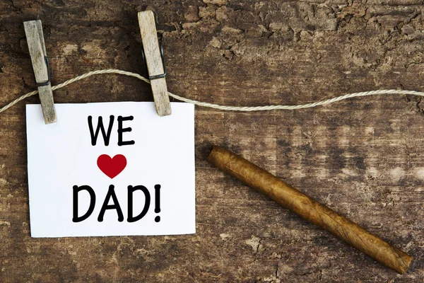 Cigarro y el signo blanco con las palabras Amamos a papá —  Fotos de Stock