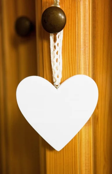 Coração branco pendurado na porta de madeira — Fotografia de Stock