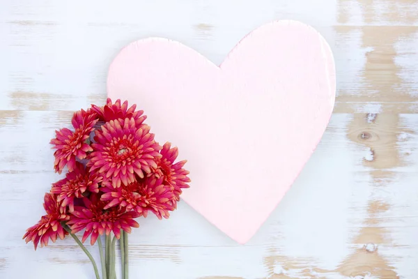 Fleurs rouges sur table en bois avec coeur — Photo