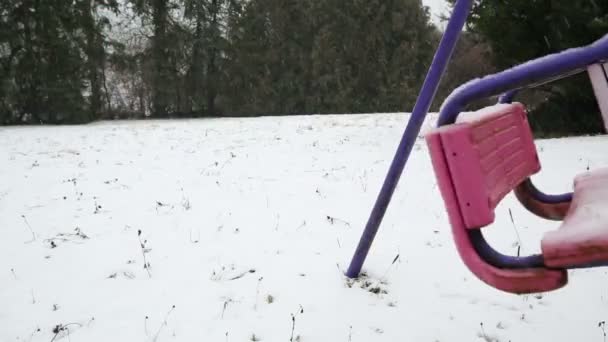 Старые качели на открытом воздухе качающиеся в снегу — стоковое видео