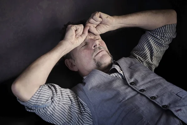 Elegantní muž v jeho 50s ležel na gauči s bolestí hlavy — Stock fotografie