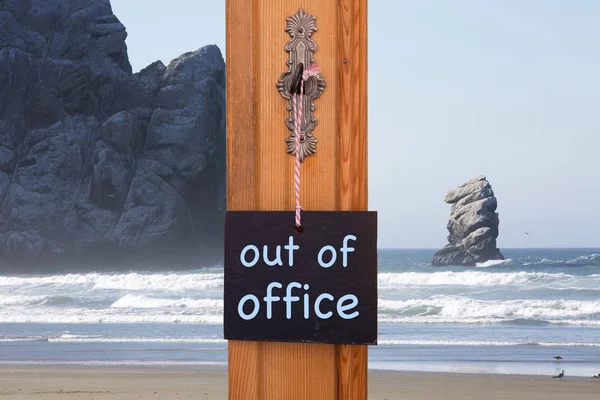 Blackboard with words Out Of Office in front of beach with rocks — Stock Photo, Image