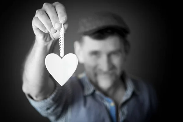 Man holding white wooden heart on a string — Stock Photo, Image