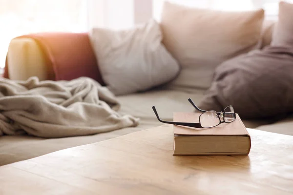 Книга с очками на столе перед диваном — стоковое фото