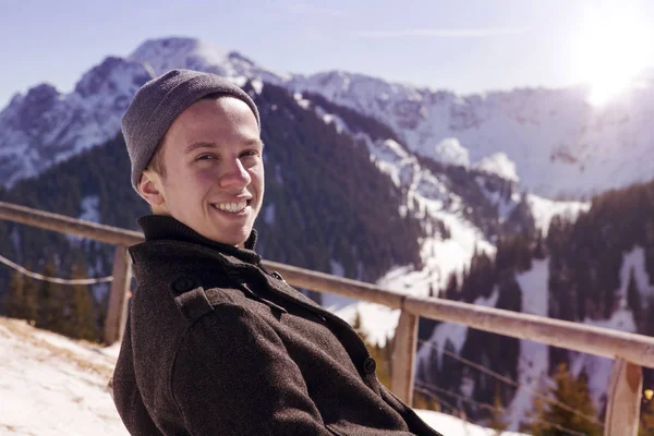 Güneşin karlı dağlarla çevrili oturan genç adam — Stok fotoğraf