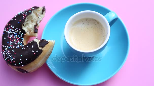 Blaue Tasse Kaffee mit halbgebissenem Donut auf rotierendem rosa Teller — Stockvideo