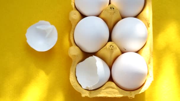 Six eggs in carton on rotating yellow plate — Stock Video