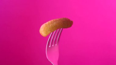 Kornişon pembe bir arka plan üzerinde çatalla döndürme