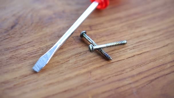 Screwdriver and screws on rotating wooden board — Stock Video