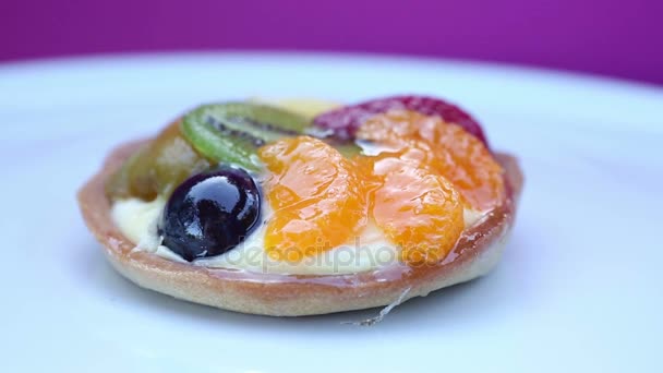 Rotating plate with round fruit tart on pink background — Stock Video