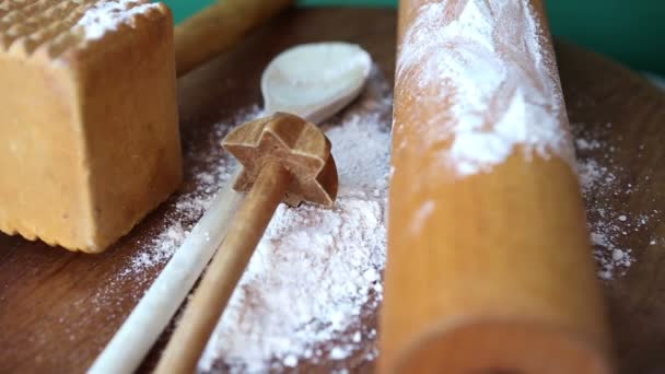 Roterende houten plank met koken lepel en gebak roller en bloem — Stockvideo