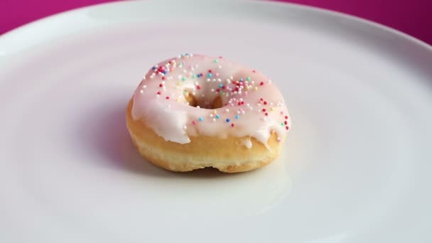 ピンクの背景にカラフルなトッピング ドーナツを回転 — ストック動画