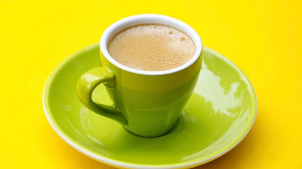 Groene kop met koffie op gele tafel — Stockfoto