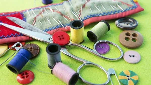 Пряжа, ножиці, голки і кнопки на зеленому табло — стокове фото
