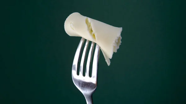 Tenedor con rebanada de queso sobre fondo verde —  Fotos de Stock