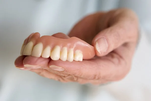 Closeup of womans hand holding a teeth denture — Stock Photo, Image