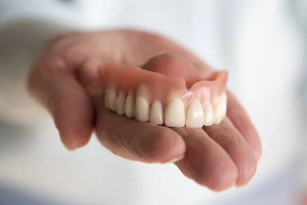 Closeup of womans hand holding a teeth denture — Stock Photo, Image