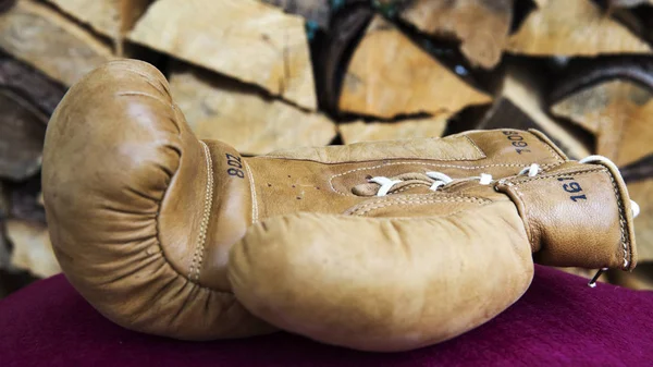 Cloesup of boxing glove in front of firewood — Stock Photo, Image