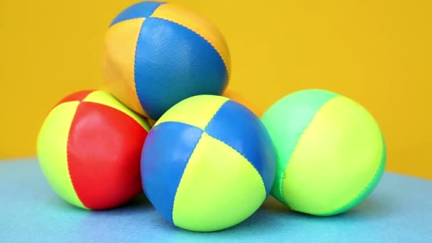 Boules de jonglerie colorées sur table tournante bleue avec fond jaune — Video