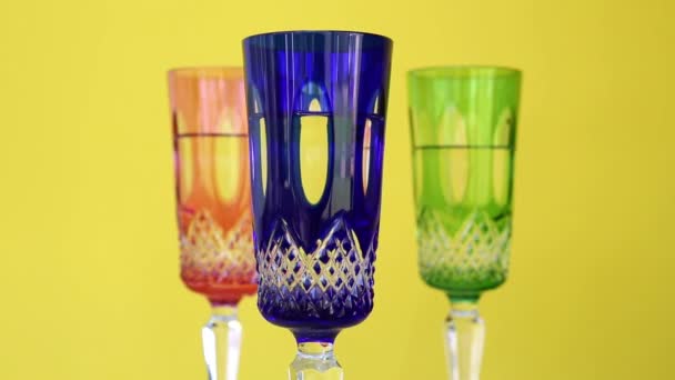 Tres vasos de cristal de colores en placa giratoria con fondo amarillo — Vídeo de stock