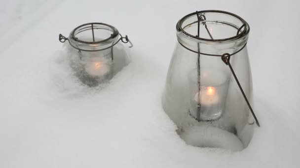 Dos velas en vasos en la nieve — Vídeos de Stock