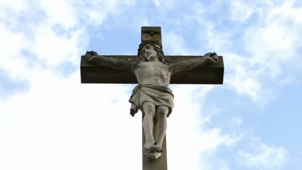 Nahaufnahme eines Steinkreuzes mit Jesus und blauem Himmel mit Wolken — Stockvideo