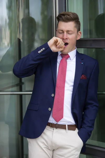 Blonder Mann im Anzug lehnt an Fenster und gähnt — Stockfoto