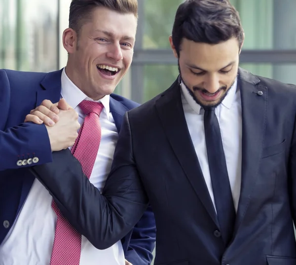 Двое мужчин в костюмах улыбаются и пожимают друг другу руки — стоковое фото